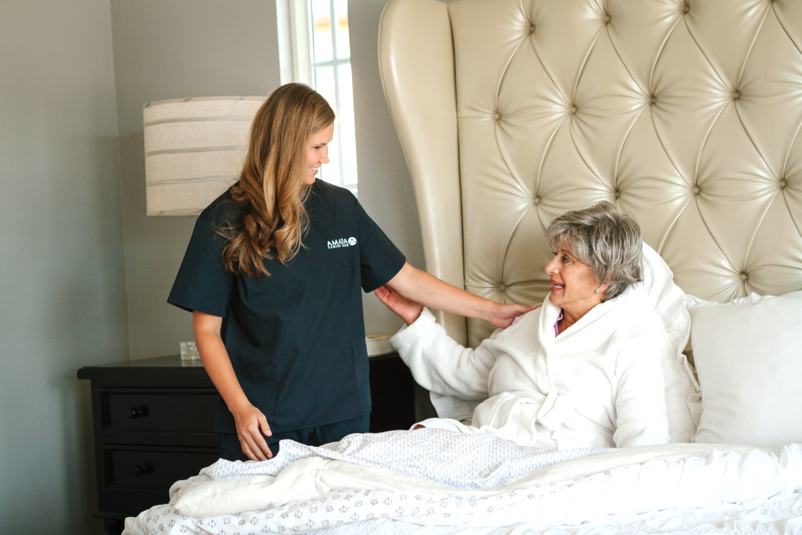 A caregiver helping an older woman get out of bed safely. 