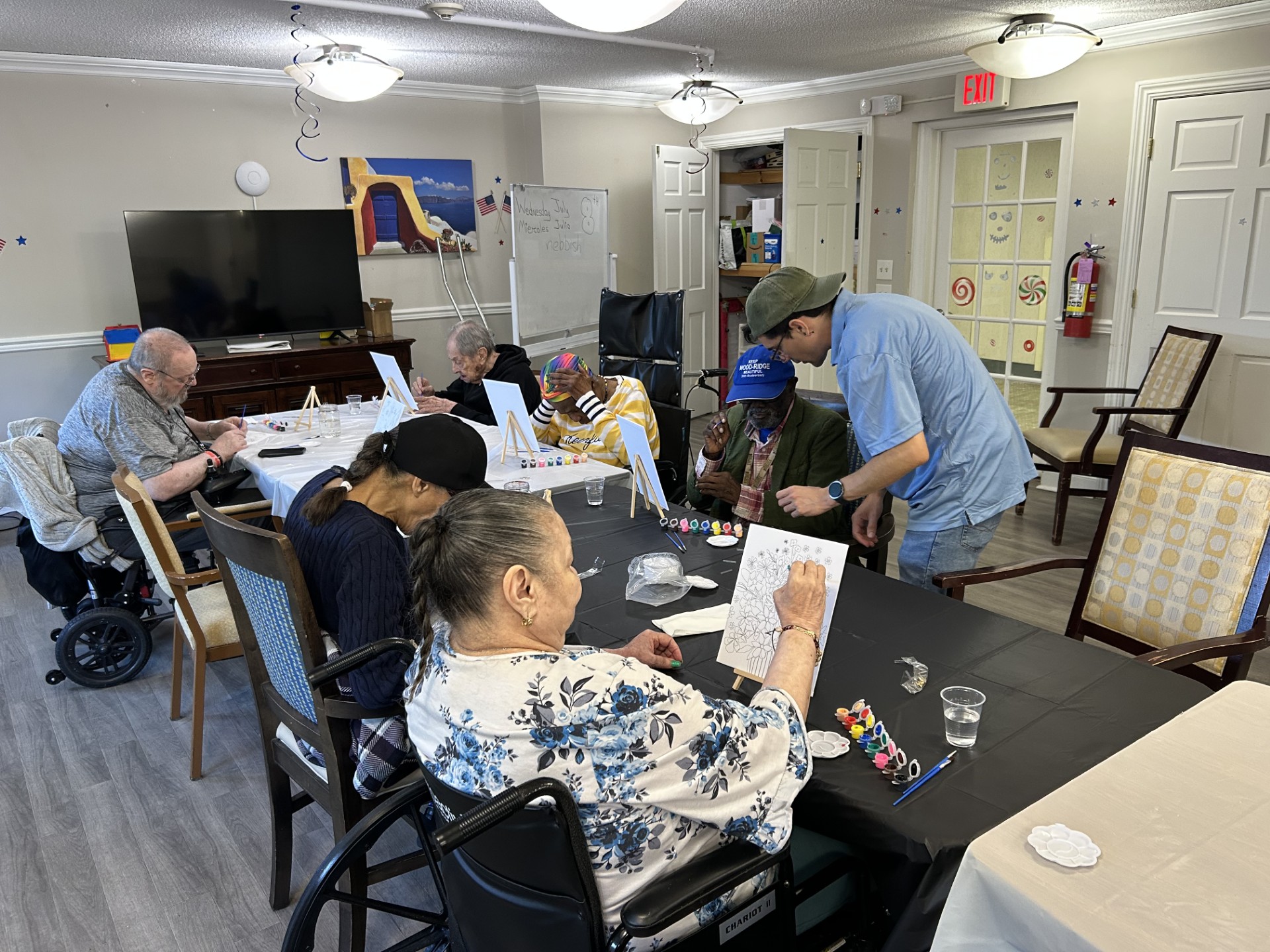 Elderly woman concentrating while painting a colorful flower canvas at Harbour View Senior Living North Bergen.
