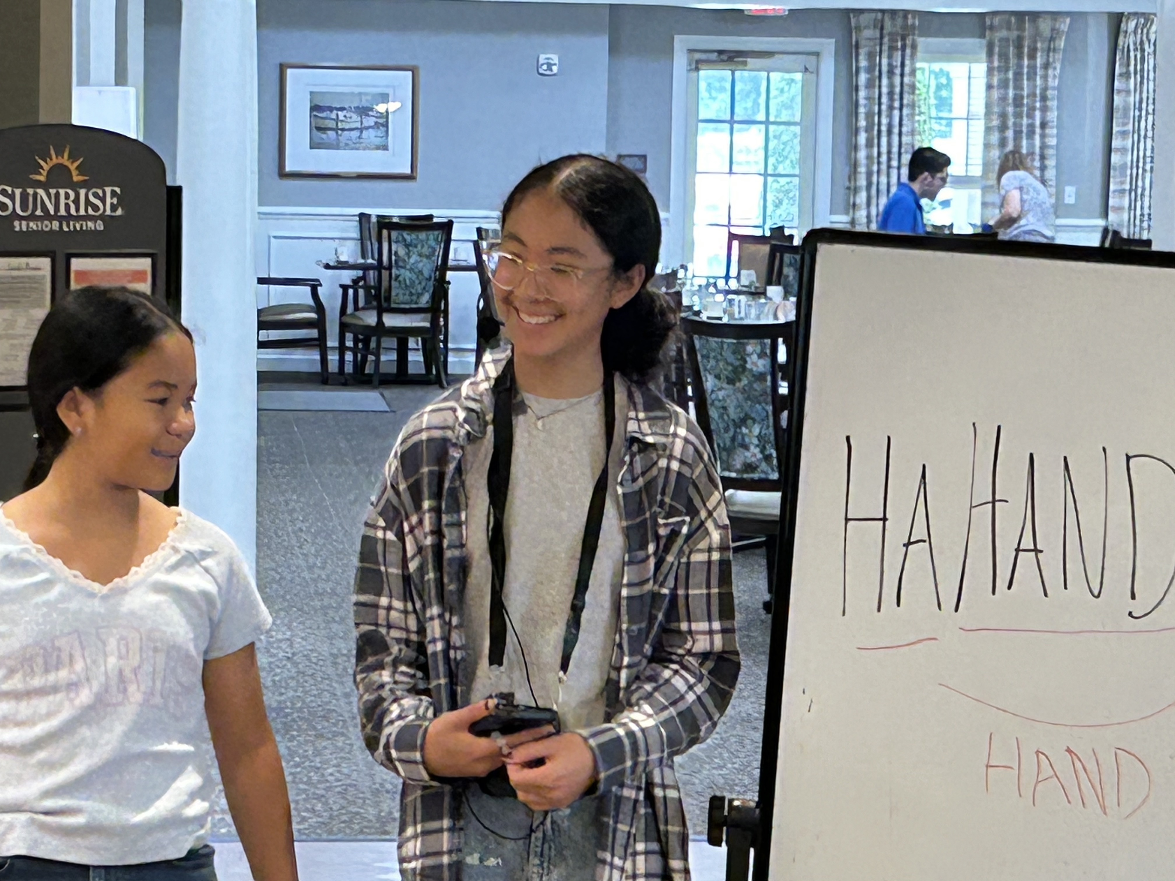 Senior residents and young volunteers engage in a word game puzzle activity together at Sunrise Senior Living in Edgewater, New Jersey.