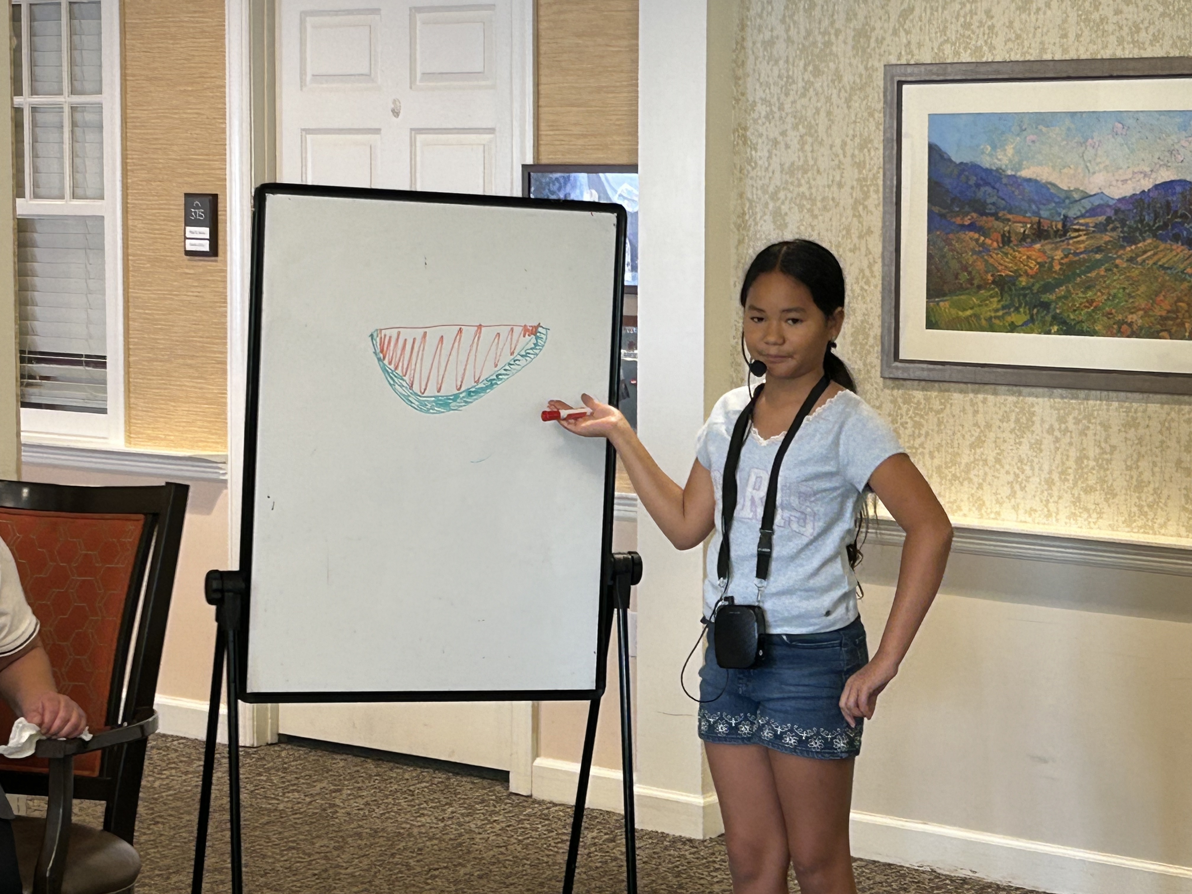 Residents and volunteers participating in Pictionary game at Sunrise Senior Living Memory Care Unit in Edgewater, New Jersey.