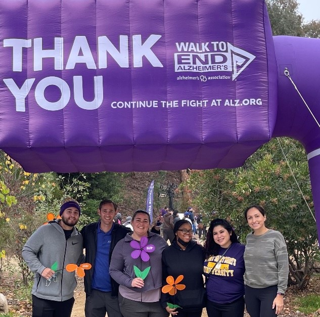 A group of people taking a photo under a sign labelled "Thank you" during the Walk to End ALZ