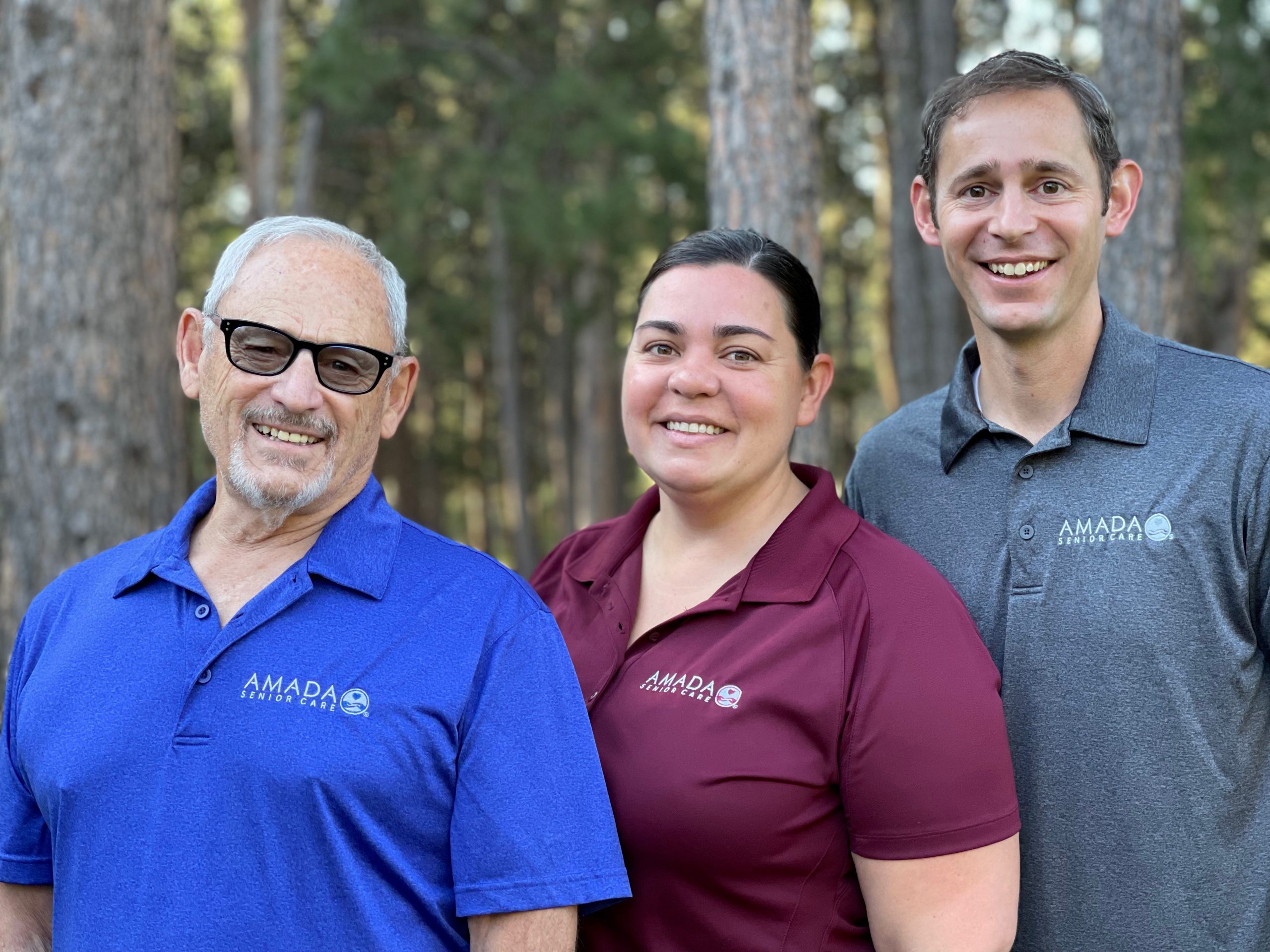 A group of Amada caretakers posing for a photo in front of the woods.