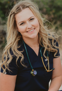 Cheyenne Nelson RN_website A woman in an Amanda uniform with a stethoscope around her neck smiles for the camera outside.
