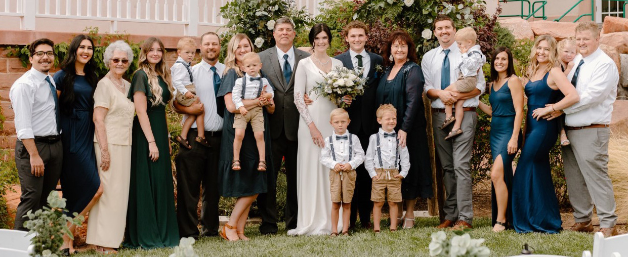 A post-wedding group photo of a large group of men, women, and children of various ages posing for a group photo.